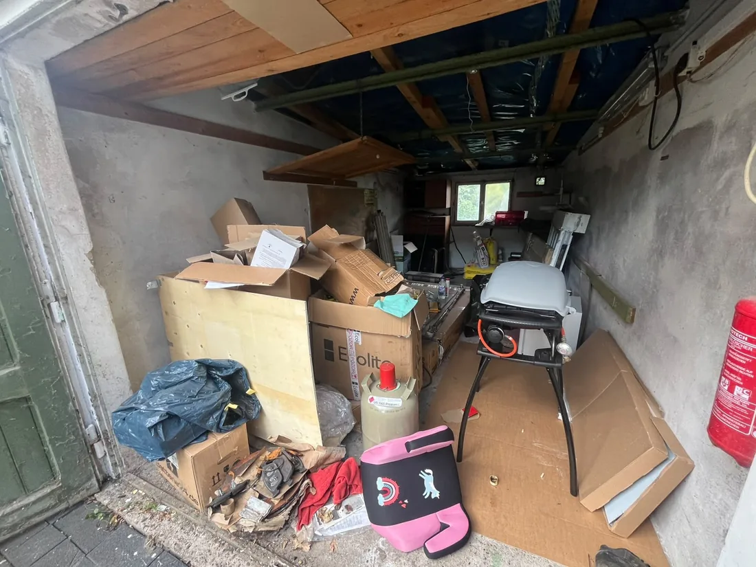 Garage in Dormagen vor der Entrümpelung: gestapelte Umzugskartons, Gasflasche, Gasgrill und Sperrgut