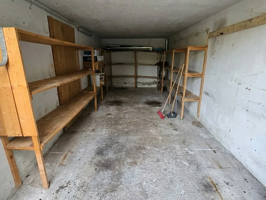 Dieselbe Garage nach der Räumung: leere Holzregale, freier Boden, besenrein übergeben